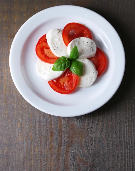 Capresesallad med mozarella ost, tomater och basilika på tallrikar, på träbord bakgrund — Stockfoto