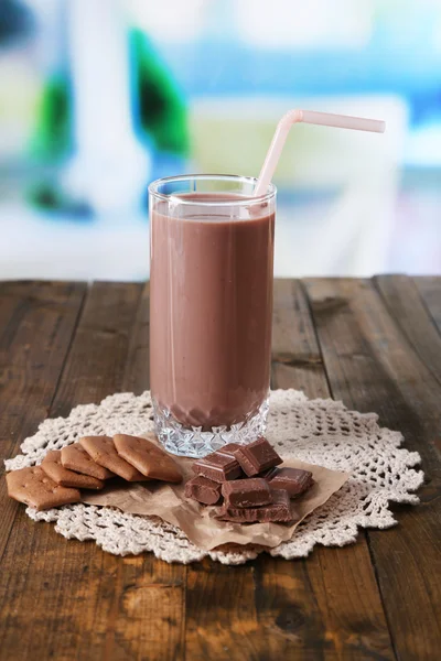 Chocolate milk in glass, on wooden table, on bright background — Stock Photo, Image