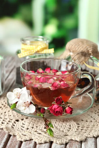 Assortiment van kruiden, thee in glazen potten en warm drinken in cup op houten tafel, op lichte achtergrond — Stockfoto