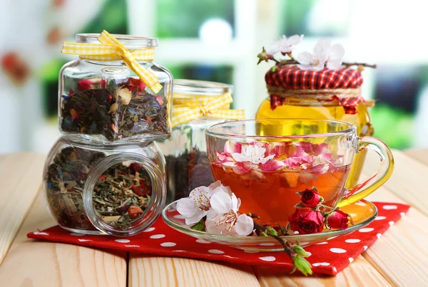 Berbagai macam herbal, madu dan teh dalam toples kaca di atas meja kayu, di latar belakang cerah — Stok Foto