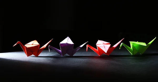 Origami jeřáb na tmavém pozadí se světlem — Stock fotografie