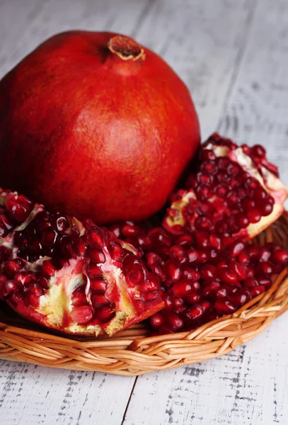 Rijp granaatappel op rieten mat op een houten achtergrond kleur — Stockfoto