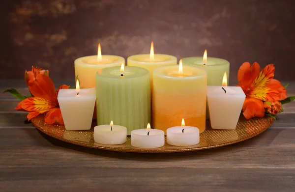 Beautiful candles with flowers on table on brown background — Stock Photo, Image