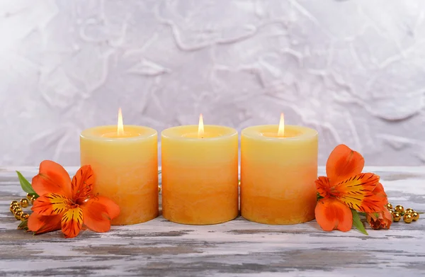 Mooie kaarsen met bloemen op tafel op grijze achtergrond — Stockfoto