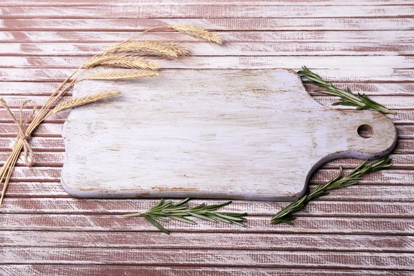 Orecchie di grano, rosmarino e tagliere su tavola di legno — Foto Stock