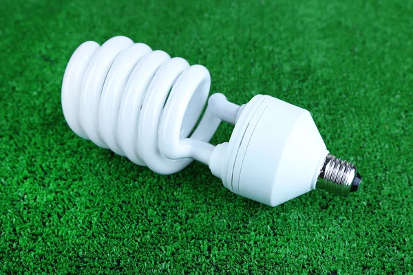 Energy saving light bulb on green grass background — Stock Photo, Image