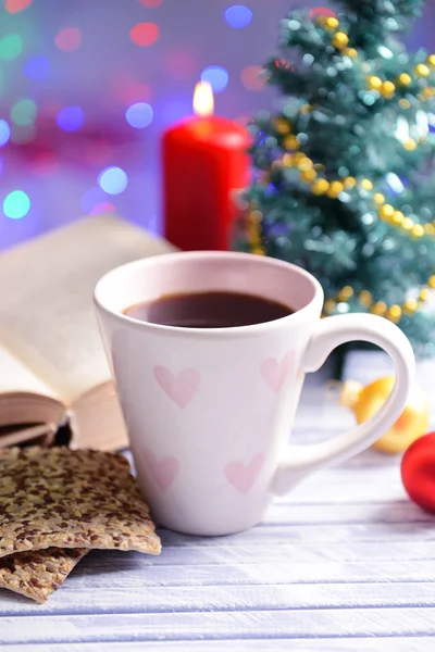 Состав книги с чашкой кофе и рождественскими украшениями на столе на ярком фоне — стоковое фото