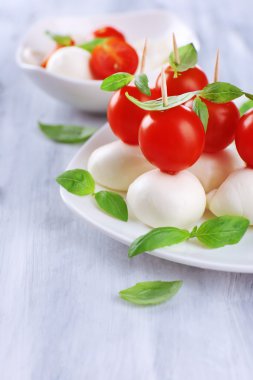 ahşap masa tabakta domates ve fesleğen ile lezzetli mozzarella peyniri