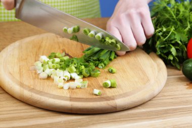 soğan Doğrama ahşap kurulu üzerinde eller mavi zemin üzerine yakın çekim