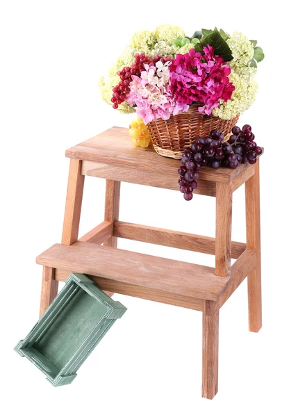 Cesta de vime com flores e frutas, em pequena escada de madeira, isolado em branco — Fotografia de Stock