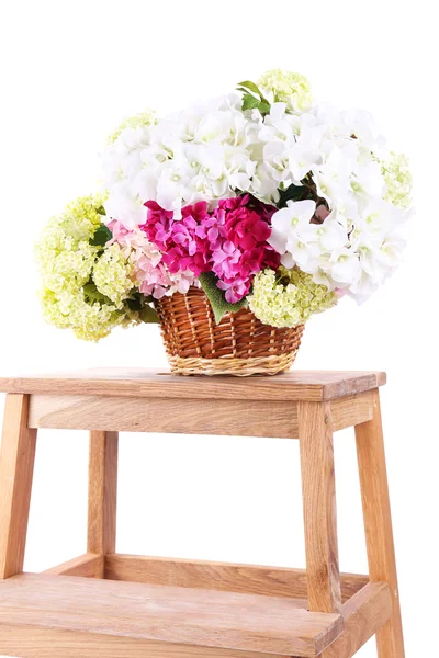 Cesta de mimbre con flores en una pequeña escalera de madera, aislada en blanco —  Fotos de Stock