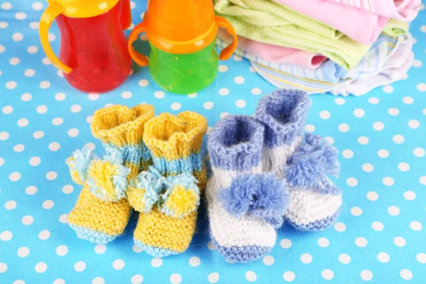 Composition with crocheted booties for baby, clothes and other things on color background — Stock Photo, Image