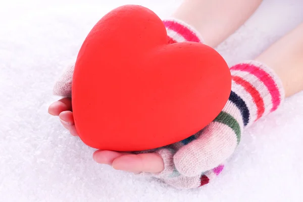 Female hands in mittens with heart on snow background — Stock Photo, Image
