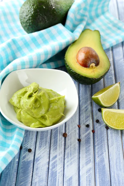 Fresh guacamole in bowl on wooden table — Stock Photo, Image