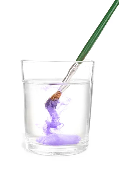 Пензлик з кольоровою фарбою у склянці води, ізольований на білому — стокове фото