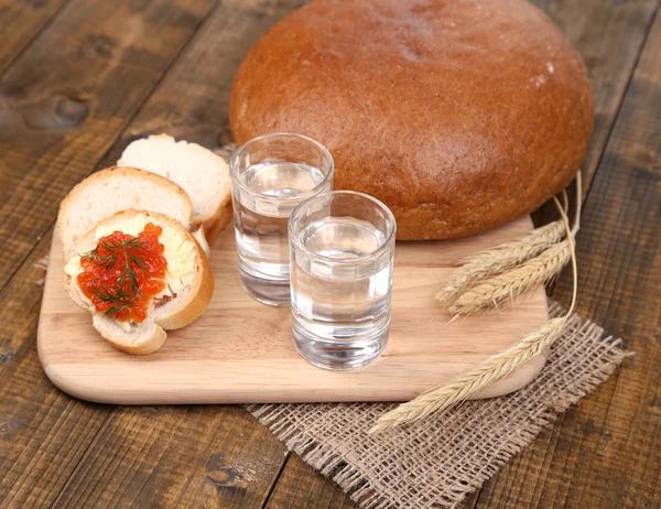 Samenstelling met glazen wodka brood en rode kaviaar op houten tafel achtergrond — Stockfoto