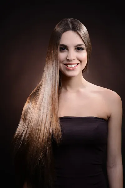Vakker ung kvinne med langt hår på mørk brun bakgrunn – stockfoto