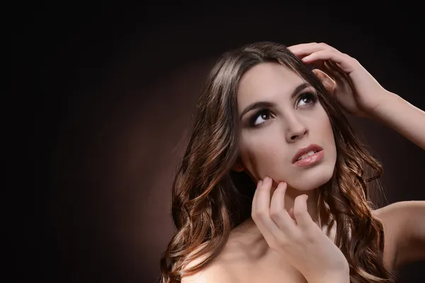 Beautiful young woman with long hair on dark brown background — Stock Photo, Image