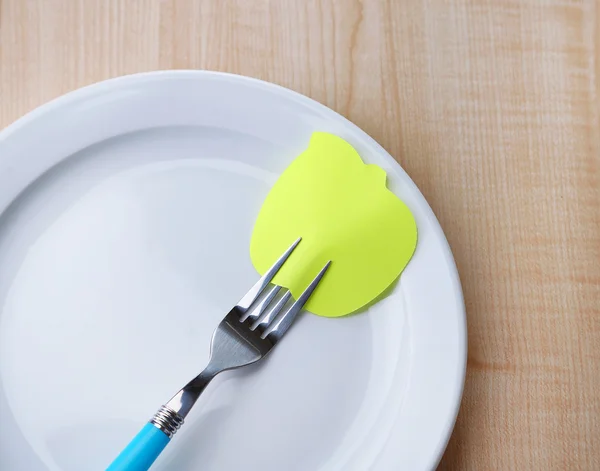 Carta a note vuote attaccata alla forchetta, su piatto, su sfondo di legno a colori — Foto Stock