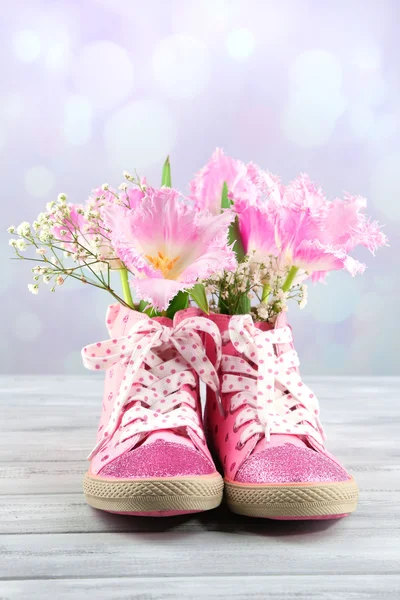 Vakre gummistøvler med blomster på trebord, på lys bakgrunn – stockfoto