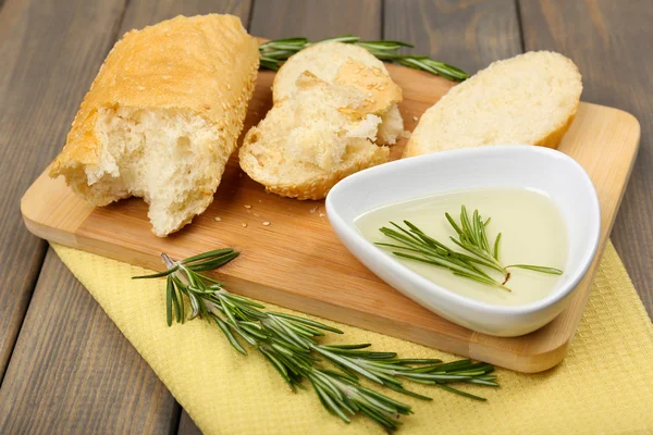 Färskt bröd med olivolja och rosmarin på träbord — Stockfoto