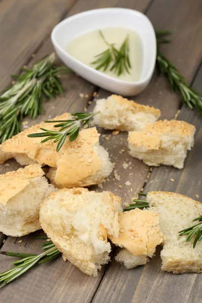 Čerstvý chléb s olivovým olejem a rozmarýnem na dřevěném stole — Stock fotografie