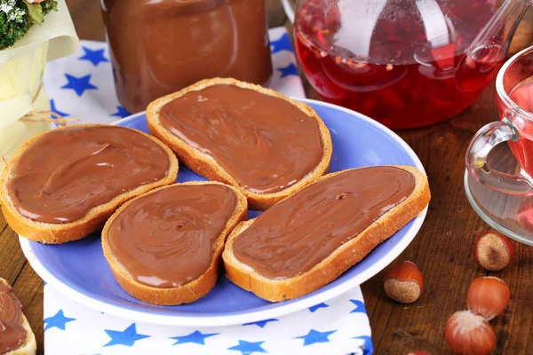 Roti dengan coklat hazelnut manis tersebar di atas piring di atas meja — Stok Foto