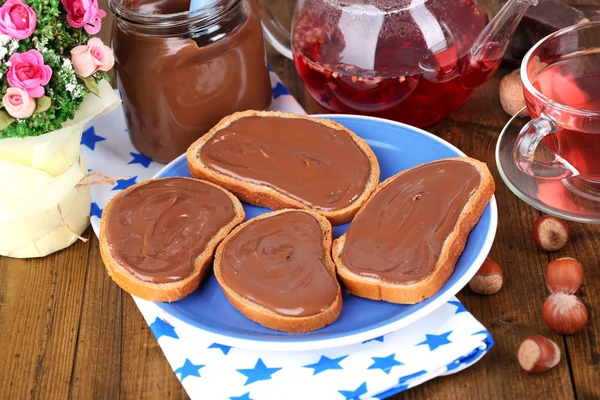 Pan con avellana de chocolate dulce extendido en el plato en la mesa — Foto de Stock