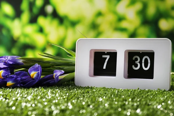 Digital alarm clock on green grass, on nature background — Stock Photo, Image