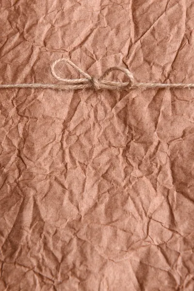 String tied in  bow on brown paper packaging close-up — Stock Photo, Image