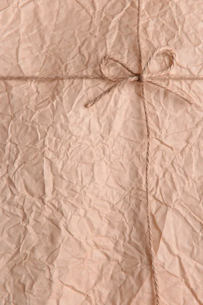 String amarrado em arco na embalagem de papel bege close-up — Fotografia de Stock