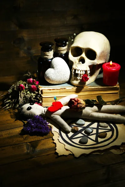 Foto conceptual de la magia del amor. Composición con cráneo, muñeca vudú, hierbas secas y vela sobre fondo de madera oscura —  Fotos de Stock