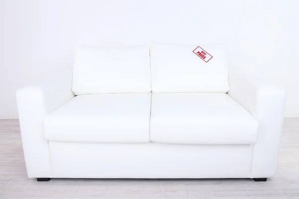 New white sofa with price on light background — Stock Photo, Image