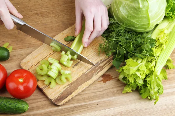 Frauenhände schneiden Sellerie auf Holzbrett, Nahaufnahme, auf Holzgrund — Stockfoto