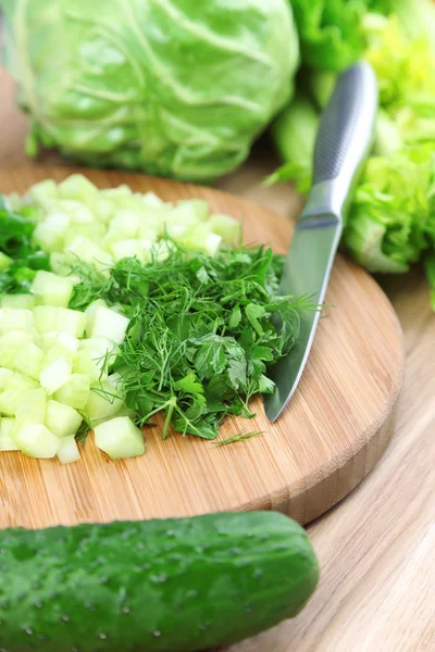 Samenstelling met gehakte kruiden op houten plank en verse groenten, op houten achtergrond — Stockfoto