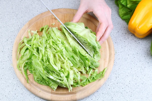 Hembra manos repollo picado sobre tabla de madera, primer plano, sobre fondo de mesa de cocina — Foto de Stock