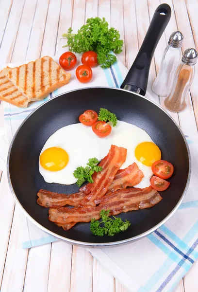 Scrambled eggs and bacon on frying pan on table close-up — Stock Photo, Image