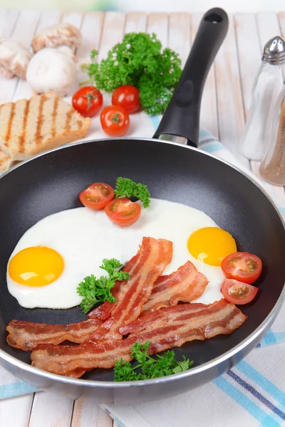 Scrambled eggs and bacon on frying pan on table close-up — Stock Photo, Image