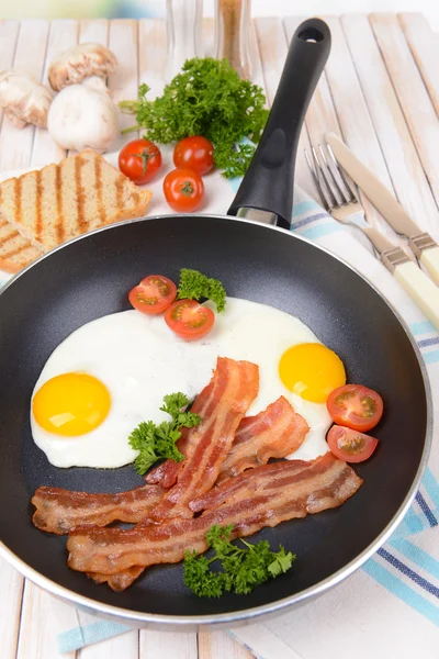 Huevos revueltos y tocino en la sartén en la mesa de cerca —  Fotos de Stock