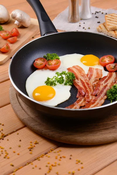 Scrambled eggs and bacon on frying pan on table close-up — Stock Photo, Image
