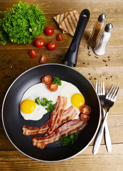 Huevos revueltos y tocino en la sartén en la mesa de cerca —  Fotos de Stock