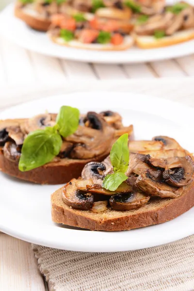 Delicious bruschetta with mushrooms on plate on table close-up — Stock Photo, Image