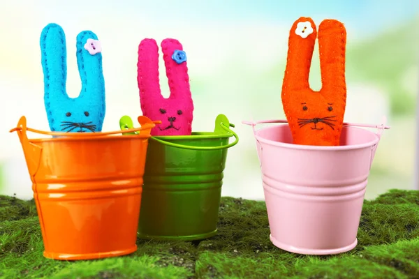 Coelhos de Páscoa artesanais engraçados em pails, na grama verde — Fotografia de Stock