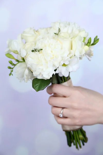 Hand holding beautiful wedding bouquet on bright background — Stock Photo, Image