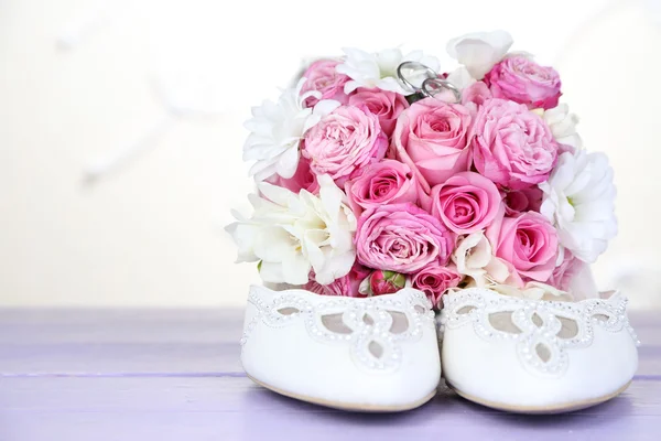 Schöner Hochzeitsstrauß und Schuhe auf dem Tisch auf hellem Hintergrund — Stockfoto
