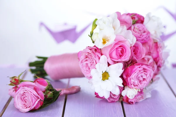 Schöner Hochzeitsstrauß und Boutonniere auf dem Tisch auf hellem Hintergrund — Stockfoto