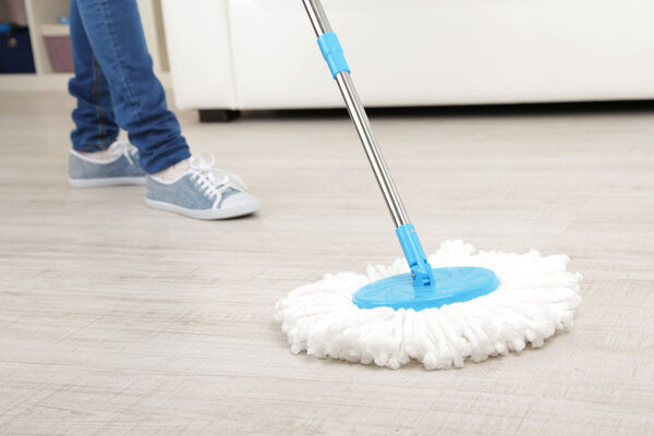 Woman with mop cleaning wooden floor from dust