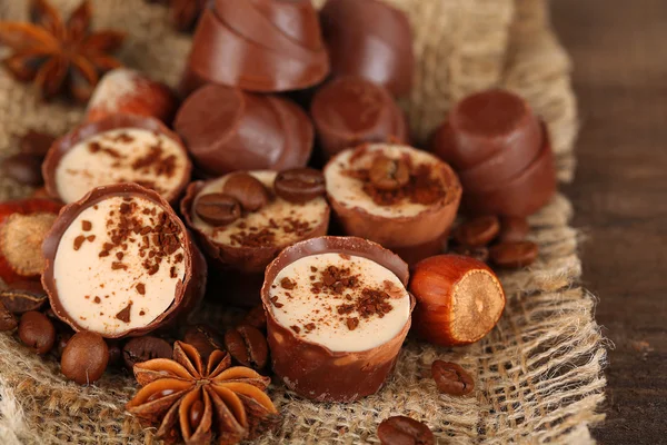 Doces de chocolate saborosos com grãos de café e nozes em fundo de madeira — Fotografia de Stock