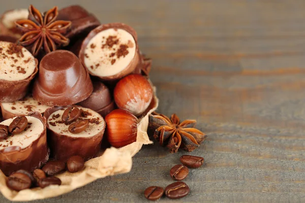 Tasty chocolate candies with coffee beans and nuts on wooden background — Stock Photo, Image