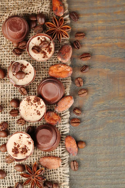 Kahve çekirdekleri ve ahşap zemin üzerine fındık ile lezzetli çikolata şekerleme — Stok fotoğraf